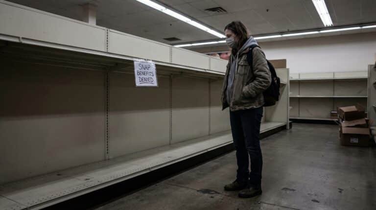 Millennial woman facing empty grocery shelves after SNAP food stamp benefits denied in 2026